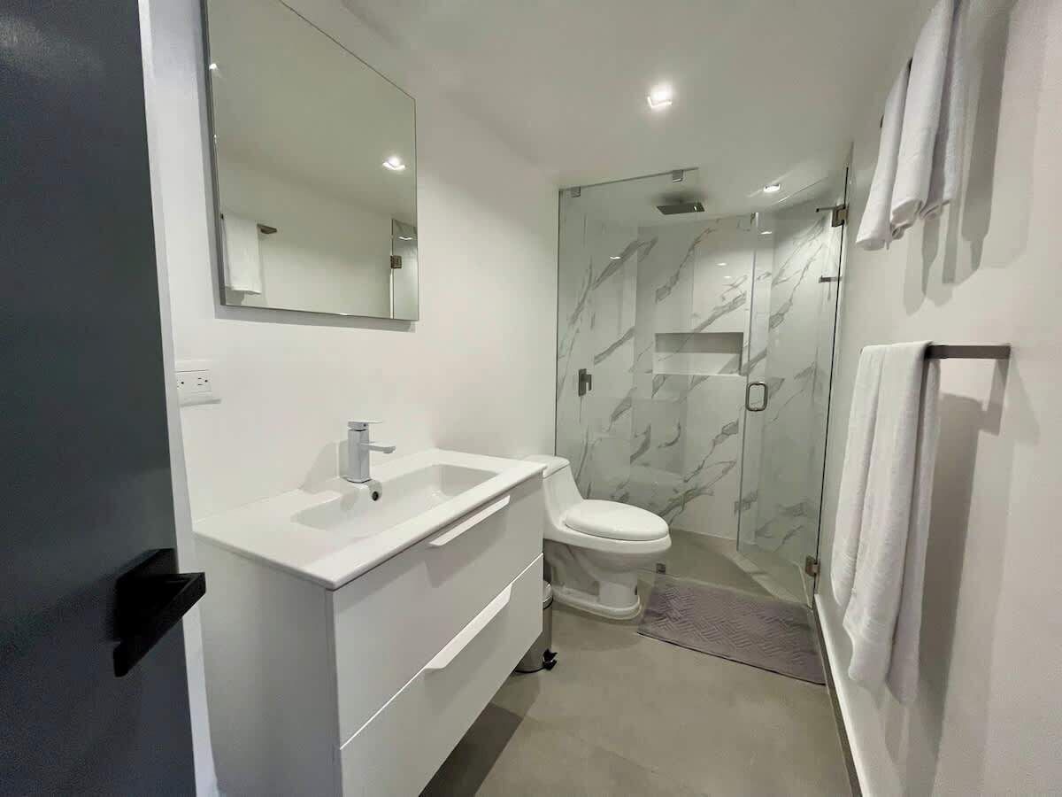Een moderne badkamer met een wit wastafelmeubel, spiegel en toilet.