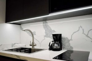 A modern kitchen with a built-in stove, a coffee maker, and a marble backsplash. - Romantic Altamira Apt: Fast WiFi & Privacy (Caracas)