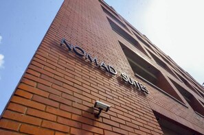 A brick building with the sign 'NOMADS SUITES' indicating a hotel or accommodation. - Romantic Altamira Apt: Fast WiFi & Privacy (Caracas)