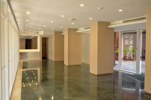 A spacious lobby with a polished floor, wooden paneling, and a glass entrance leading outside. - Romantic Altamira Apt: Fast WiFi & Privacy (Caracas)