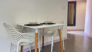 A dining area with a white table and chairs, a mirror on the wall, and a door in the background. - Romantic Altamira Apt: Fast WiFi & Privacy (Caracas)