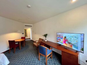 Ein Hotelzimmer mit Essbereich, Fernseher und Pflanze.