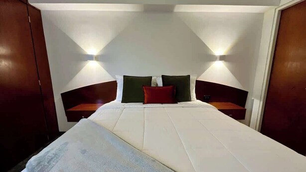 Ett hotellrum med en stor säng, två sängbord och väggmonterad belysning.