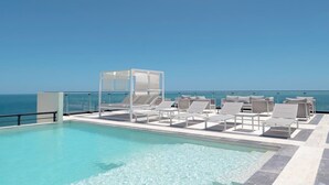 A rooftop infinity pool with lounge chairs and a glass balustrade overlooking the ocean. - Dpto. de 2 Hab. Frente a la Playa & Amenidades Top (Progreso)