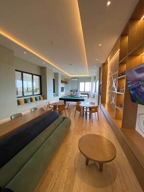 A modern interior with a pool table, seating area, and a wall with a decorative shelf.