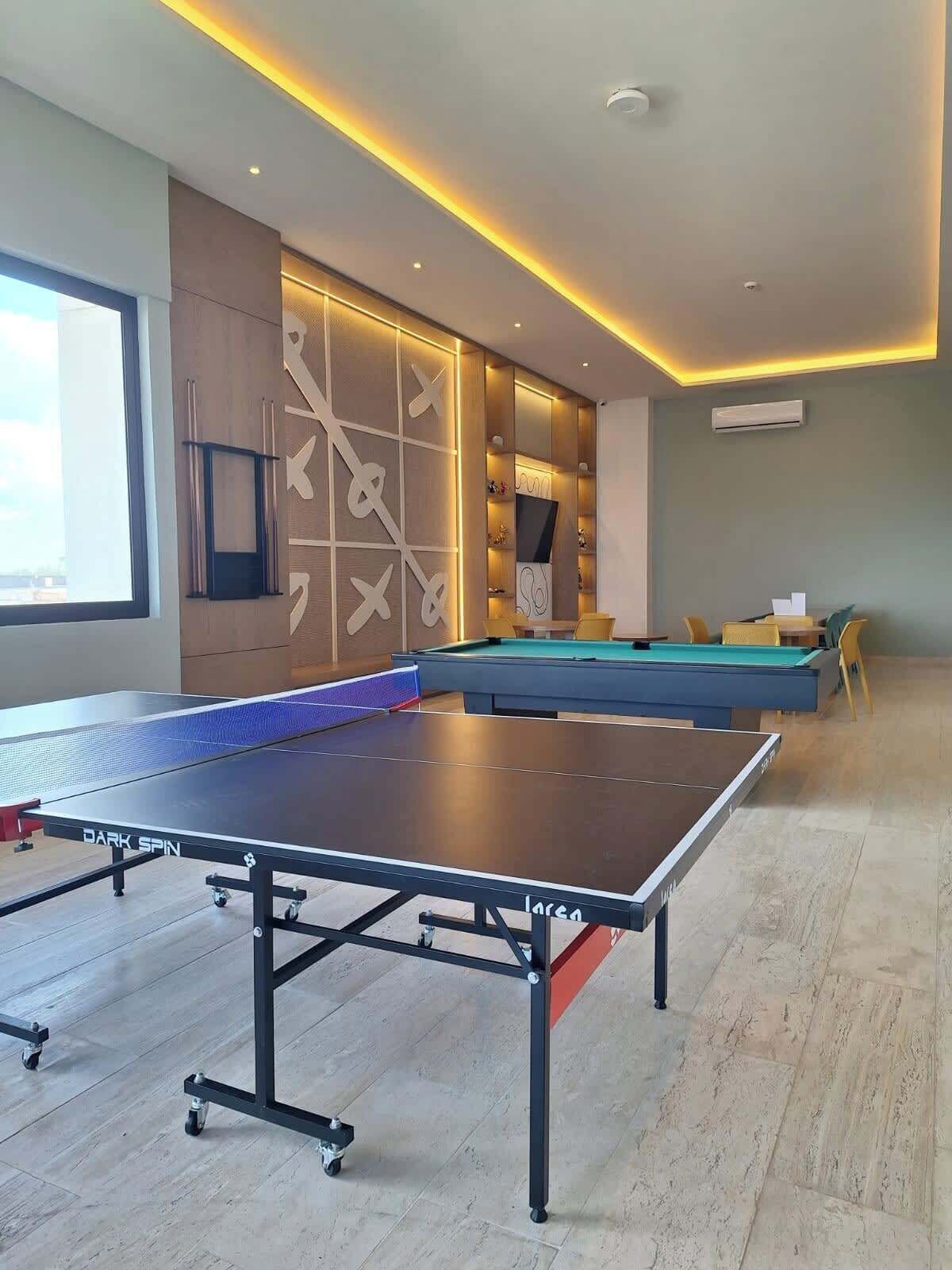A room with a ping pong table, a pool table, and a billiards table.
