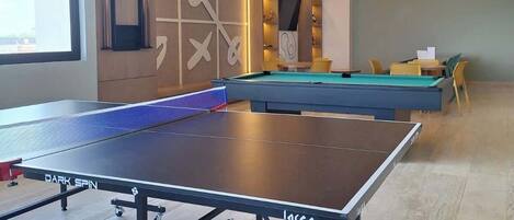A room with a ping pong table, a pool table, and a billiards table.