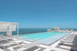 A poolside area with lounge chairs and a view of the ocean.
