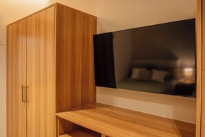 Ein Zimmer mit einem Holfischschrank, einem flachbildfernseher an der Wand und einer hölzernen Sitzbank.