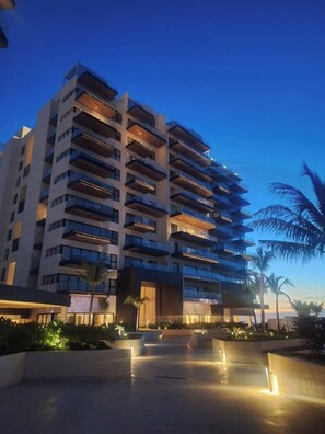 A multi-story hotel with balconies, a landscaped courtyard, and palm trees.