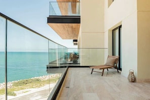 Ein Balkon mit freiem Blick auf das Meer, ein Korbstuhl und eine Vase.