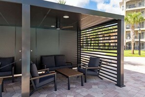 An outdoor seating area with a modern design, featuring a sofa, chairs, and a table. - Lakeview Condo Private Jacuzzi & Resort Pool (Orlando)