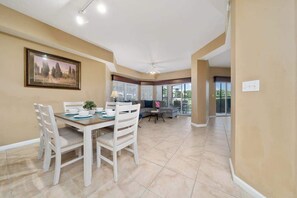 A dining area with a table and chairs, a sofa, and a ceiling fan. - GoUppers® Lakeview Condo Private Jacuzzi & Resort (Orlando)
