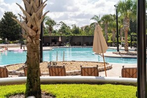 A pool area with lounge chairs and umbrellas, surrounded by palm trees and greenery. - Lakeview Condo Private Jacuzzi & Resort Pool (Orlando)