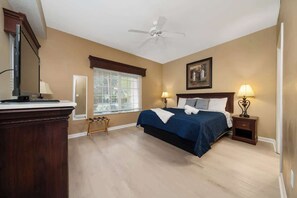 A bedroom with a bed, bedside lamps, a ceiling fan, a window with blinds, and a dresser. - Lakeview Condo Private Jacuzzi & Resort Pool (Orlando)