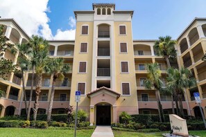 A multi-story hotel with a central entrance, balconies, and palm trees. - Lakeview Condo Private Jacuzzi & Resort Pool (Orlando)