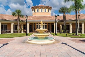 A courtyard with a central fountain, a building with a tiled roof, and palm trees. - Lakeview Condo Private Jacuzzi & Resort Pool (Orlando)