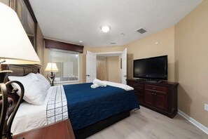 A hotel room with a bed, a television, a lamp, and a window with blinds. - GoUppers® Lakeview Condo Private Jacuzzi & Resort (Orlando)