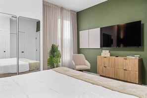Quarto com cama, televisão, guarda-roupa e espelho.
