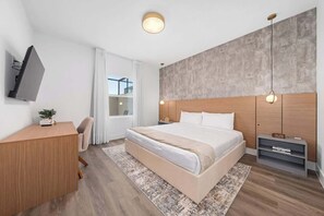 A modern hotel room with a large bed, a desk, a TV, and a view of the city. - Davenport Disney Home Private Pool (Davenport)