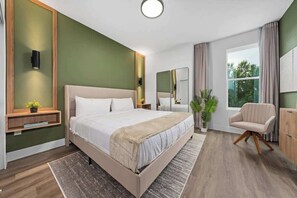 A modern bedroom with a large bed, bedside tables, a mirror, a chair, and a window. - Davenport Disney Home Private Pool (Davenport)