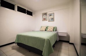 Ein Schlafzimmer mit einem Bett, einem Nachttisch und einem Fenster.