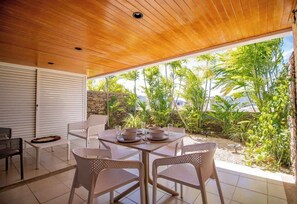 A dining area with a table set for four, surrounded by white chairs, under a wooden ceiling. - Loma Real Pampatar Terraza Piscinas (Pampatar)