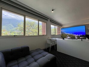Ett rum med ett stort fönster, ett skrivbord, en stol och en soffa.
