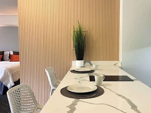 A hotel room with a dining table set for two, a potted plant, and a bed with a white comforter. - Remodelado y Cómodo: Internet Rápido + Zona Top (Caracas)
