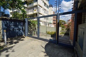 A gated entrance with a metal gate, a concrete pathway, and a building with multiple floors in the background. - Remodelado y Cómodo: Internet Rápido + Zona Top (Caracas)