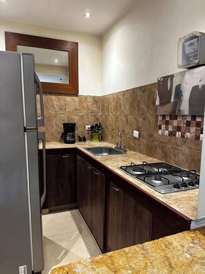 Eine Küche mit einem Edelstahl-Kühlschrank, einem Gasherd, einer Spüle und Holzschränken.
