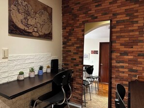 Eine moderne Küche mit Backsteinwand, einer großen Karte und einem Essbereich mit Stühlen und Tisch.