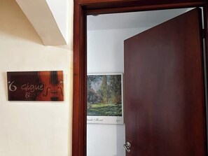 A door leading to a room with a framed painting and a sign on the wall. - Villa Suites en Chapinero Alto (Bogotá)