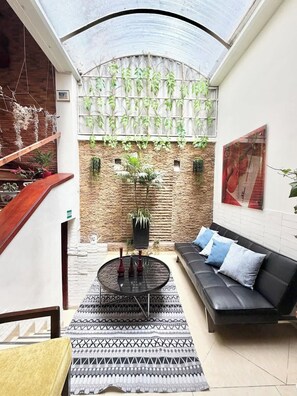 Ein modernes Wohnzimmer mit einem schwarzen Ledersofa, einem gemusterten Teppich und einem runden Couchtisch mit Vasen.