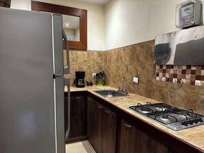 A kitchen with a refrigerator, stove, sink, and a coffee maker. - Villa Suites en Chapinero Alto (Bogotá)