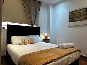 Ein Hotelzimmer mit Bett, Nachttisch, Lampe und einem Bild an der Wand.