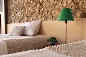 Ein Bett mit einem punktierten Bettüberwurf, eine grüne Stehlampe und ein kleiner Blumentopf.