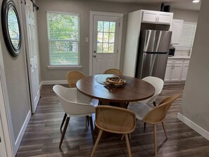 A dining area with a round table, white chairs, and wicker chairs. - Six Flags · AT&T Stadium · Family House (Arlington)
