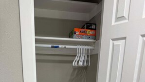 Ein Schrank mit weißer Tür, Holzboden und einem Regal mit Kisten.