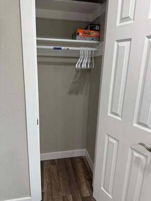 Ein Schrank mit weißer Tür, Holzboden und einem Regal mit Kisten.
