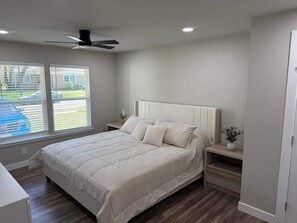 A bedroom with a bed, nightstands, a ceiling fan, and a window with blinds. - Six Flags · AT&T Stadium · Family House (Arlington)