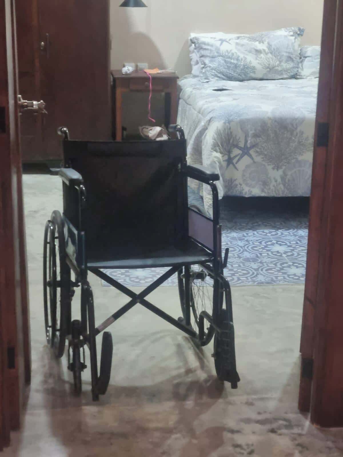 Ein Rollstuhl in einem Zimmer mit einem Bett und einem Nachttisch.