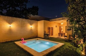 A swimming pool with a pink flamingo decoration, surrounded by a well-lit patio area with outdoor furniture. - La María House: lux, comfort, and pool (Merida)