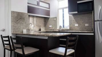 A kitchen with a granite countertop, dark cabinetry, and two bar stools.