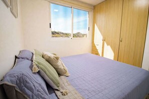 A bedroom with a bed, a window, and a wardrobe. - Apartamento Frente al Mar en Pampatar (Pampatar)