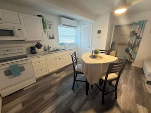 A kitchen with white cabinets, a microwave, an oven, and a dining table with chairs. - Altamonte Springs Apt: Pool & City Views, Prime (Altamonte Springs)