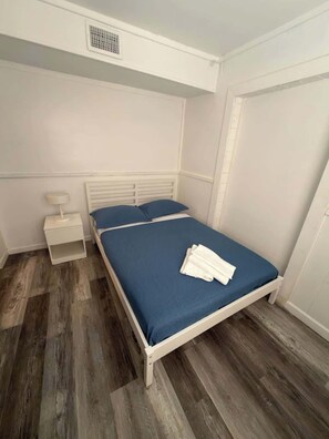 A single bed with a blue mattress and white bedding, a bedside table with a lamp, and a wardrobe. - Altamonte Springs Apt: Pool & City Views, Prime (Altamonte Springs)