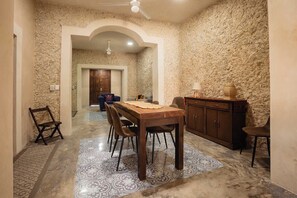 A dining area with a wooden table and chairs, a cabinet, and a patterned floor. - Casa Colonial c/Alberca Privada (Merida)