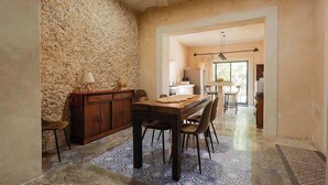 A dining area with a rustic stone wall, a wooden table, and chairs. - Casa Colonial c/Alberca Privada (Merida)