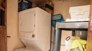 A laundry room with stacked washing machines, a shelf with cleaning supplies, and a patterned floor. - Casa Colonial c/Alberca Privada (Merida)